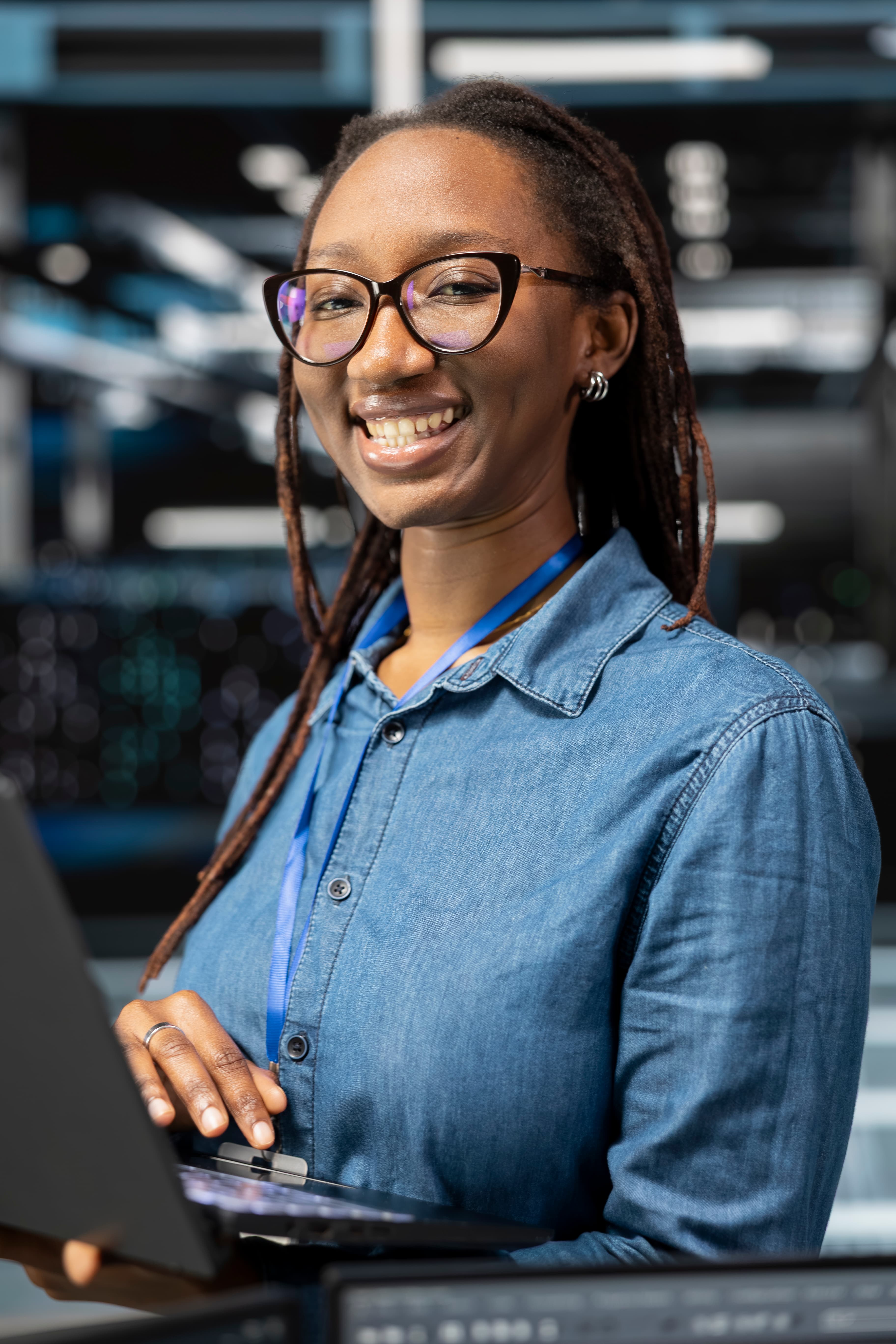 A smiling data centre technician standing in front of server infrastructure.